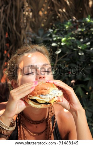 Happy woman in a restaurant eating a fast food hamburger