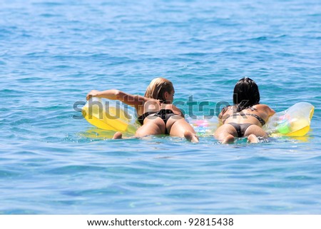Beautiful young Two Women lying on air bed in the sea