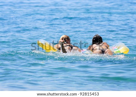 Beautiful young Two Women lying on air bed in the sea
