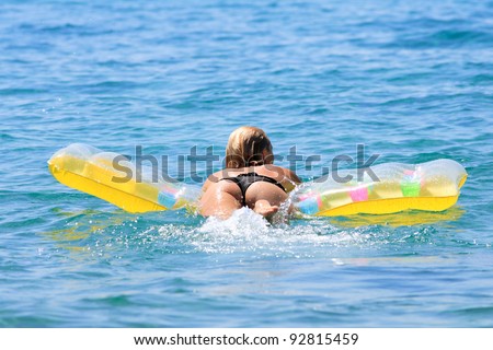 Beautiful young woman lying on air bed in the sea