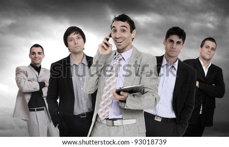 Successful and confident business leader talking on the phone and holding a tablet computer in front of his team