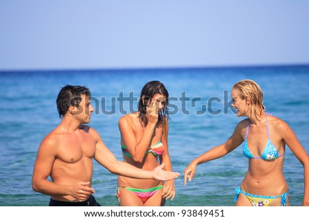Group of three friends - man and women - on the beach having lots of fun in their vacation in Greece