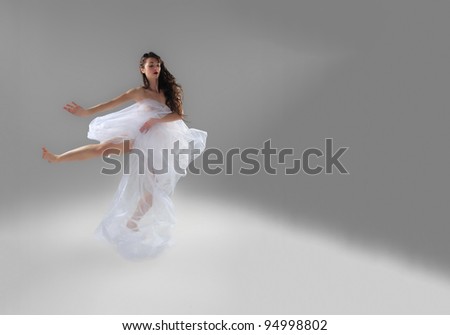 Young female dancer posing over gray background