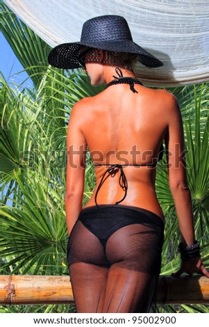 Young and sexy bikini model with hat  in tropical environement