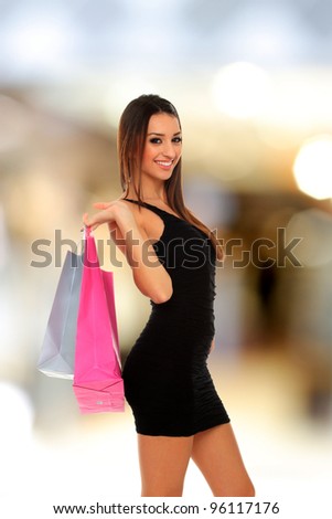 lovely brunette woman in light dress with colorful shopping bags at the mall
