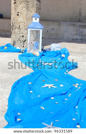 Starfish and shells on blue cloth and lantern at Greek wedding