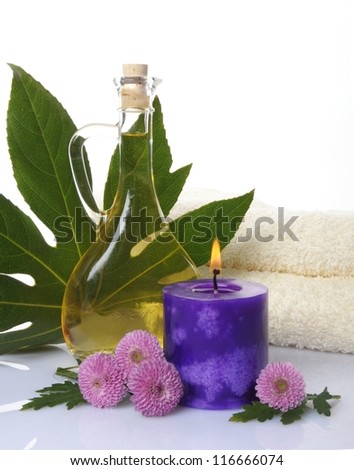 spa treatment with oil, candle and flowers on white