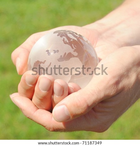 glass globe in the hand in front of a green background