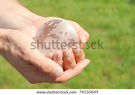 glass globe in the hand in front of a green background