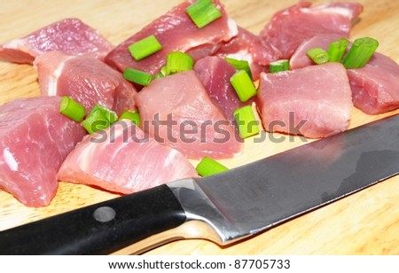 fresh uncooked beef meat sliced in cubes on board with carving knife