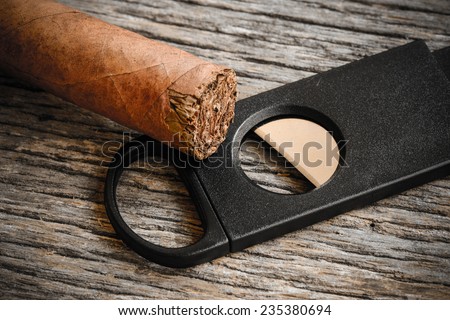 Cigar and Cigar Cutter on Rustic Wood Background