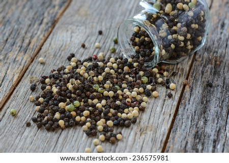 Peppercorn spilling out of a glass jar