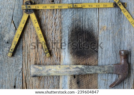 Old Tape Measure and Hammer for Construction on Rustic Wood Background