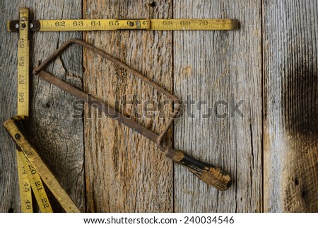 Old Tape Measure and Saw for Construction on Rustic Wood Background