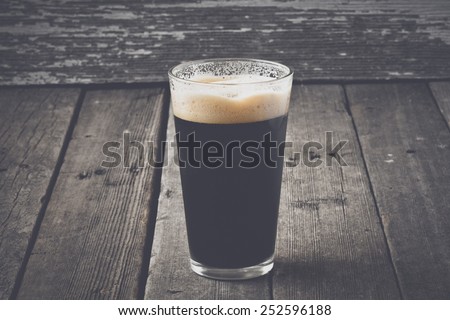 Pint of Dark Beer on Wood Background with Vintage Film Style