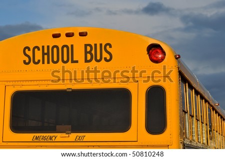 Back of Black and Yellow School Bus with cloudy Sky