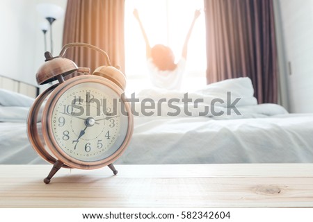 alarm clock . background happy woman stretching in bed after waking up, sunlight in morning.