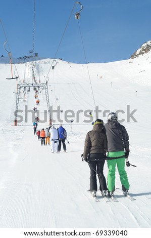 T bar ski lift pulling skiers up the slope. Perfect winter in European Alps.