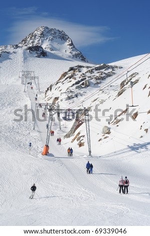 T bar ski lift pulling skiers up the slope. Perfect weather for snow fun in Tirol