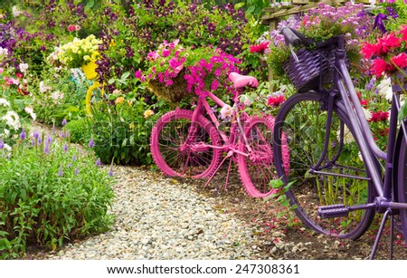 Whimsical garden art bicycles, baskets filled with blooming flowers spilling over into the blooming garden./ Painted Bicycles as Garden Art Planters