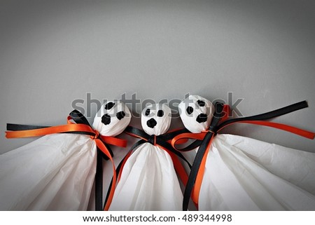 Halloween concept background : Three halloween ghosts DIY made from white tissue paper, black and orange ribbon on gray background