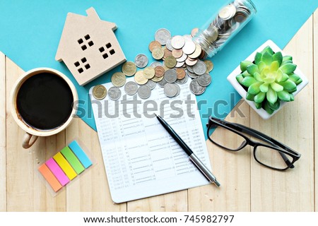 Business, finance, saving money, property loan or mortgage concept :  Top view or flat lay of wood house model, saving account book or financial statement and coins on office desk table