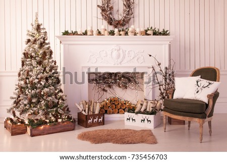 Christmas decor of a bright stylish living room with a vintage armchair, fireplace, Christmas tree and candles