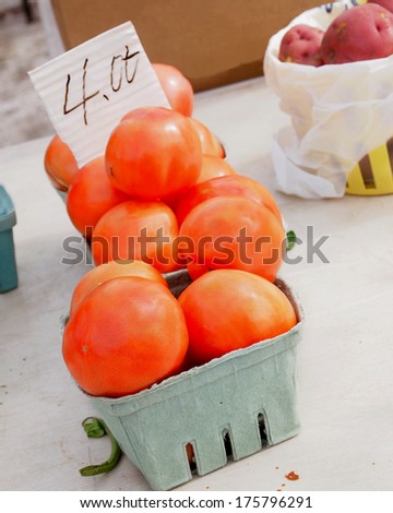 Tomatoes and a few potatoes for sale at a local farmer\'s market on a winter day.