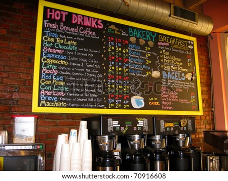 A colorful handwritten menu on a chalkboard against a brick wall in a coffee house.