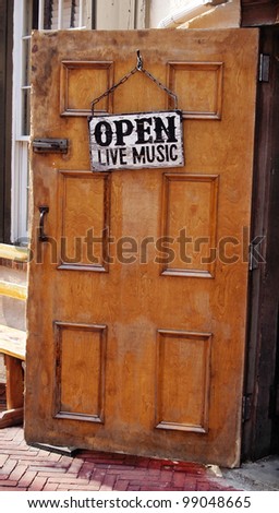 Open door to a local bar with a sign announcing \