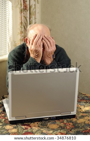 senior man holding head in frustration while looking at computer