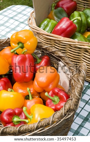 Basket of yellow, green, orange, capsicums on table stall