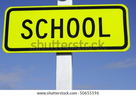 Zebra crossing sign with school set against blue sky