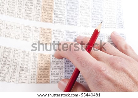 Man working out figures from newspaper holding pencil