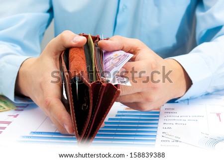Businessman hand holding a opened leather wallet and taking money