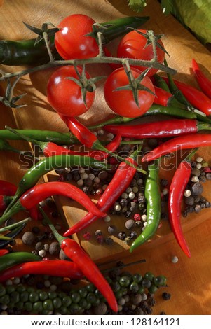 different types of hot peppers and cherry tomatoes on a wooden cutting board