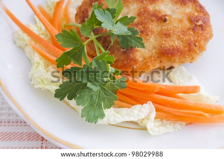 Chop chicken with carrot sticks and lettuce on a plate. Close-up. Top view.