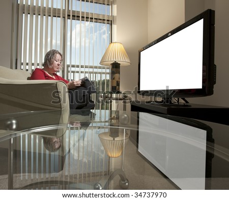 Woman reading in fron to a blank TV screen, reflected in a glass coffee table. Screen is blank to insert image or message
