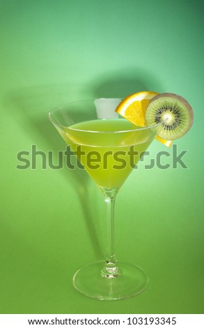 Green cocktail with fresh orange and kiwi over green background