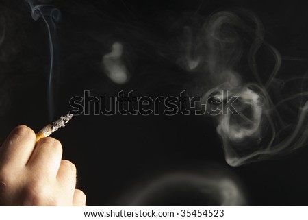 Hand holding lit cigarette with smoke rings