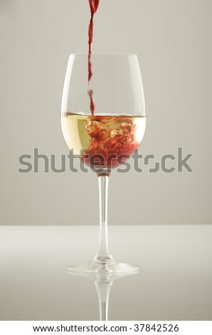 Red wine poured into a glass of white wine
