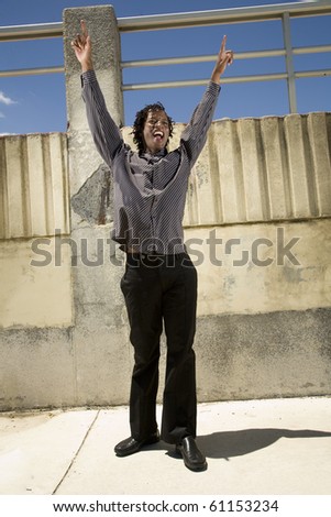 Black South African man, with funky outfit, putting his hands in the air in elation.