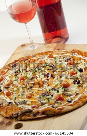Delicious pizza with rose wine on a wood board, ready to be enjoyed.