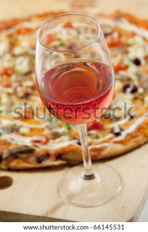 Delicious pizza with rose wine on a wood board, ready to be enjoyed.