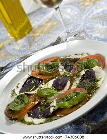 Tomato slices and cheese slices, topped with basil pesto and olive oil.