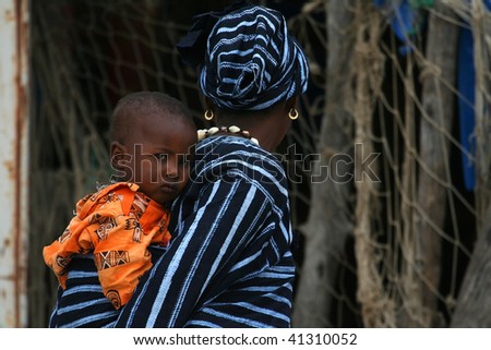 SENEGAL - FEBRUARY 18: African mother carries her child back in the port of Elinkine, point of departure for boats bound for Spain on February 18, 2007 in Elinkine, Casamance, Senegal.
