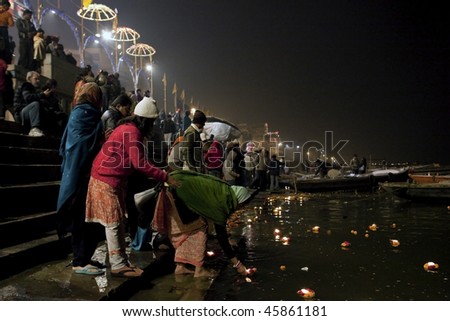 INDIA - DECEMBER 31: Believers make offerings to the river Ganges in the Aarti ceremony with flowers and candles, December 31, 2009 in Varanasi, India