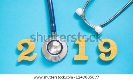 Stethoscope w/ 2019 gold wooden number on blue background. Happy New Year for healthcare and medical banner/calendar cover. Creative idea for new trend in medicine treatment and diagnosis concept.