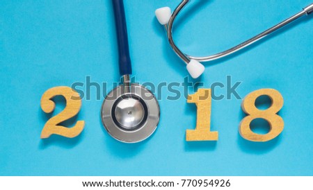 Stethoscope w/ 2018 gold wooden number on blue background. Happy New Year for healthcare and medical banner/calendar cover. Creative idea for new trend in medicine treatment and diagnosis concept.