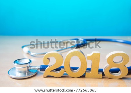 Stethoscope w/ 2018 gold wood number on doctor desk blue background. Happy New Year for healthcare and medical. Creative idea for new trend in medicine treatment and diagnosis concept. Copy space.